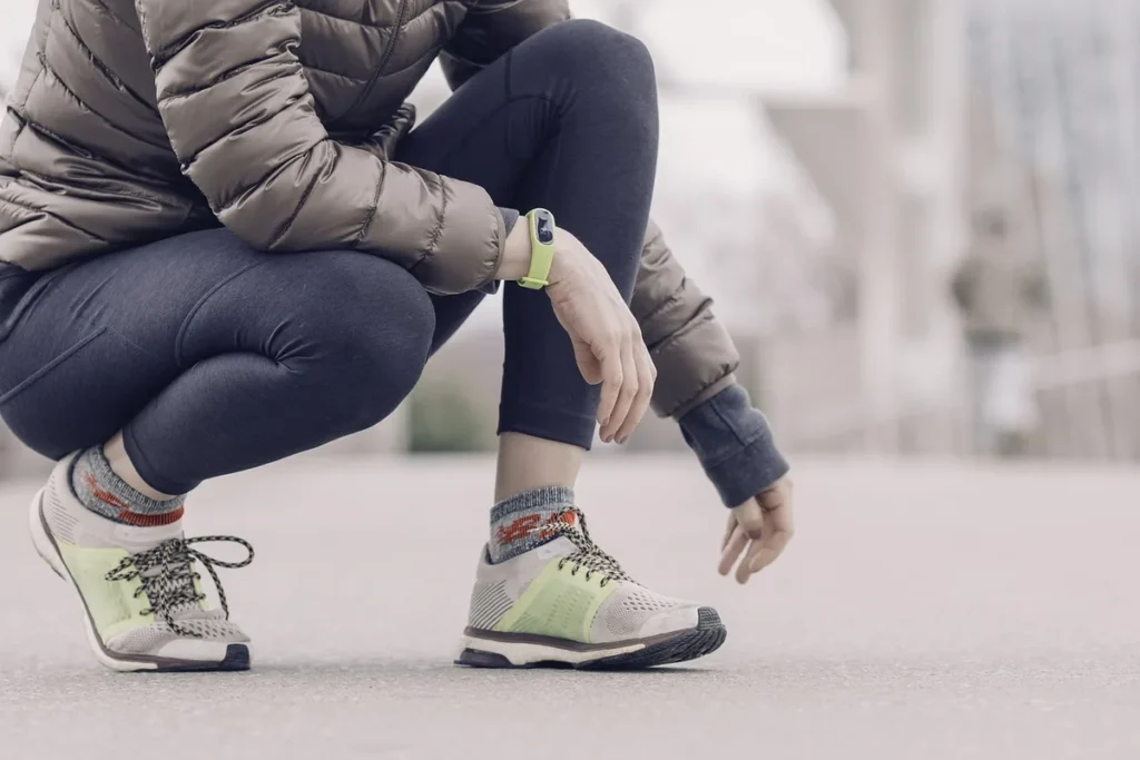Opaska fitness na nadgarstku kobiety przy rozciąganiu na ulicy, kroki i trening jako dwa źródła ruchu
