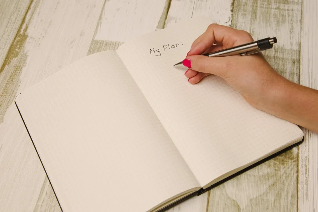 Otwarty notes w kratkę i długopis, gotowe do rozpisania przykładowego mezocyklu na 5 tygodni