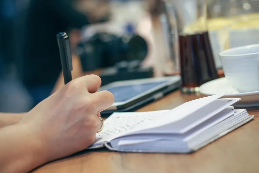 Zapisywanie notatek długopisem w notesie, tak jak prowadzi się dziennik treningowy